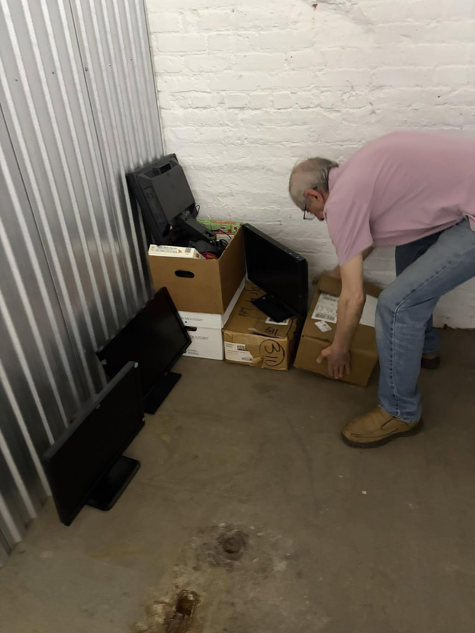 Volunteer moving donated computers and monitors into storage unit